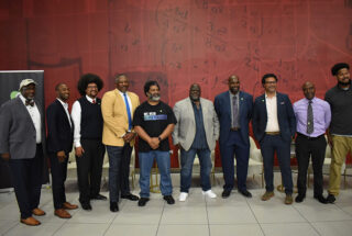 A group of Black male educators stand together at an event.