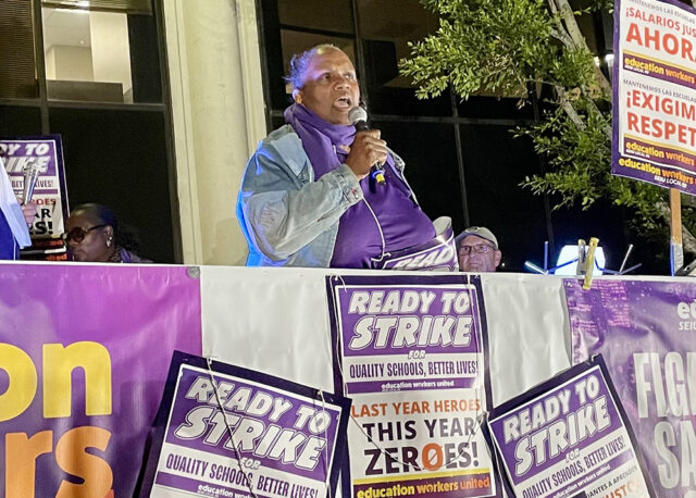 Edna Logan speaks at a rally surrounded by signs that say "Ready to Strike"