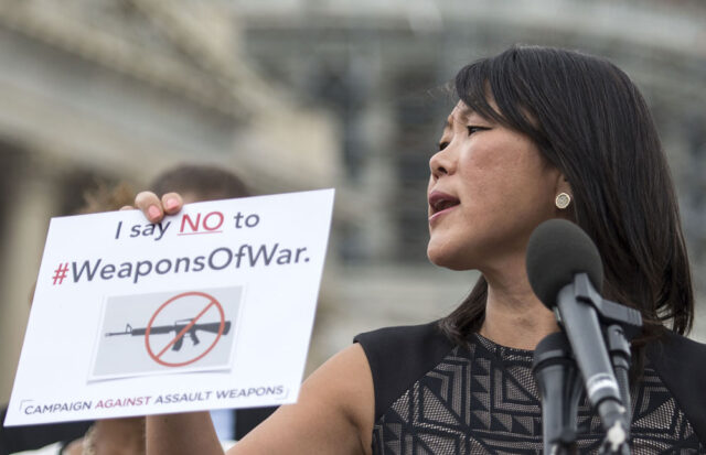 Po Murray speaks at an event; she holds a sign that says I say no to weapons of war.