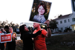 A woman embraces Mark Barden, who holds up a picture of his son Daniel, a victim of the Sandy Hook shooting, during a vigil 