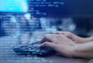 A conceptual image of hands on a computer keyboard indicating cybersecurity issues